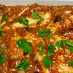 A skillet of golden-brown Chicken Provencal topped with tomatoes and fresh herbs.